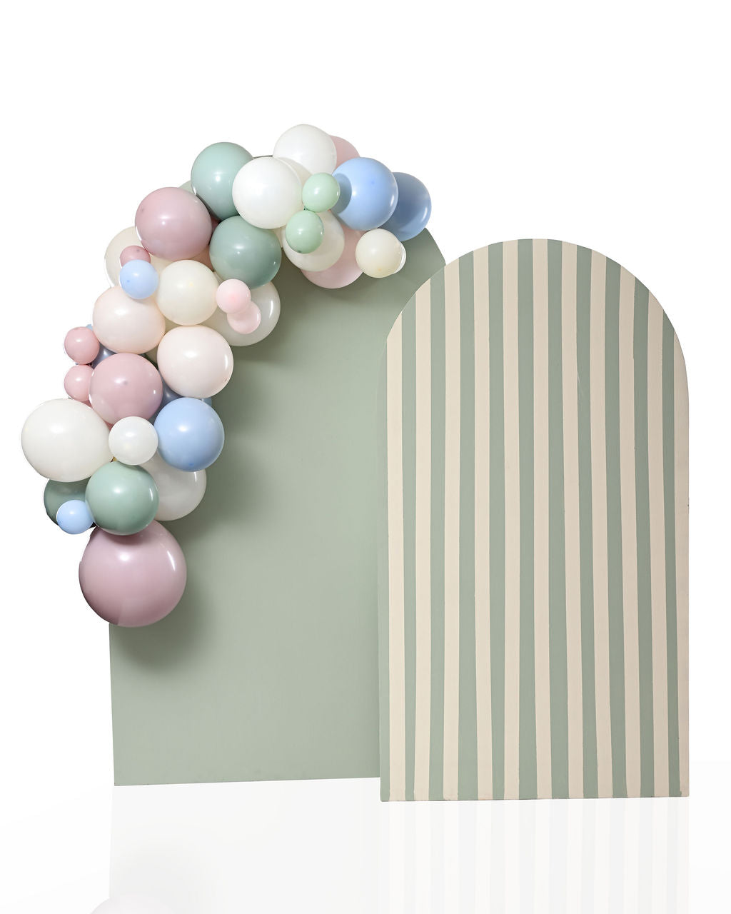 Close-up of a pastel balloon garland in sage green, dusty pink, cream, and dusty blue cascading down the side of a two-tone arch backdrop — solid sage green on the left panel and cream-and-sage stripes on the right.