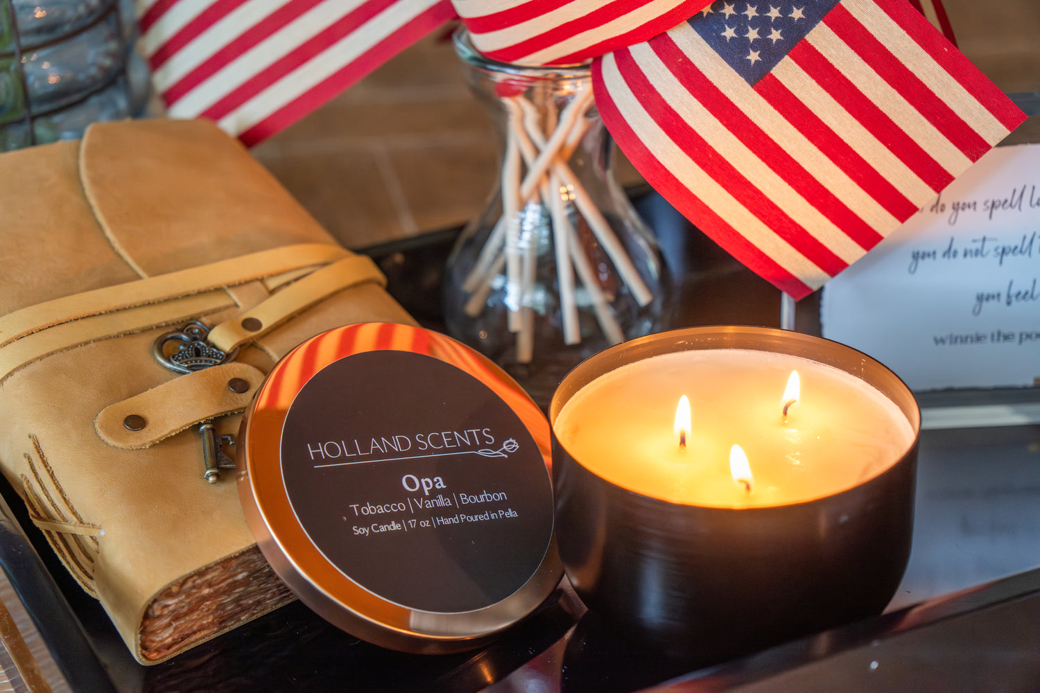 4th of July display with a leather journal, Holland Scents Opa candle, and American flag from Thistles Flower Market, Pella, Iowa