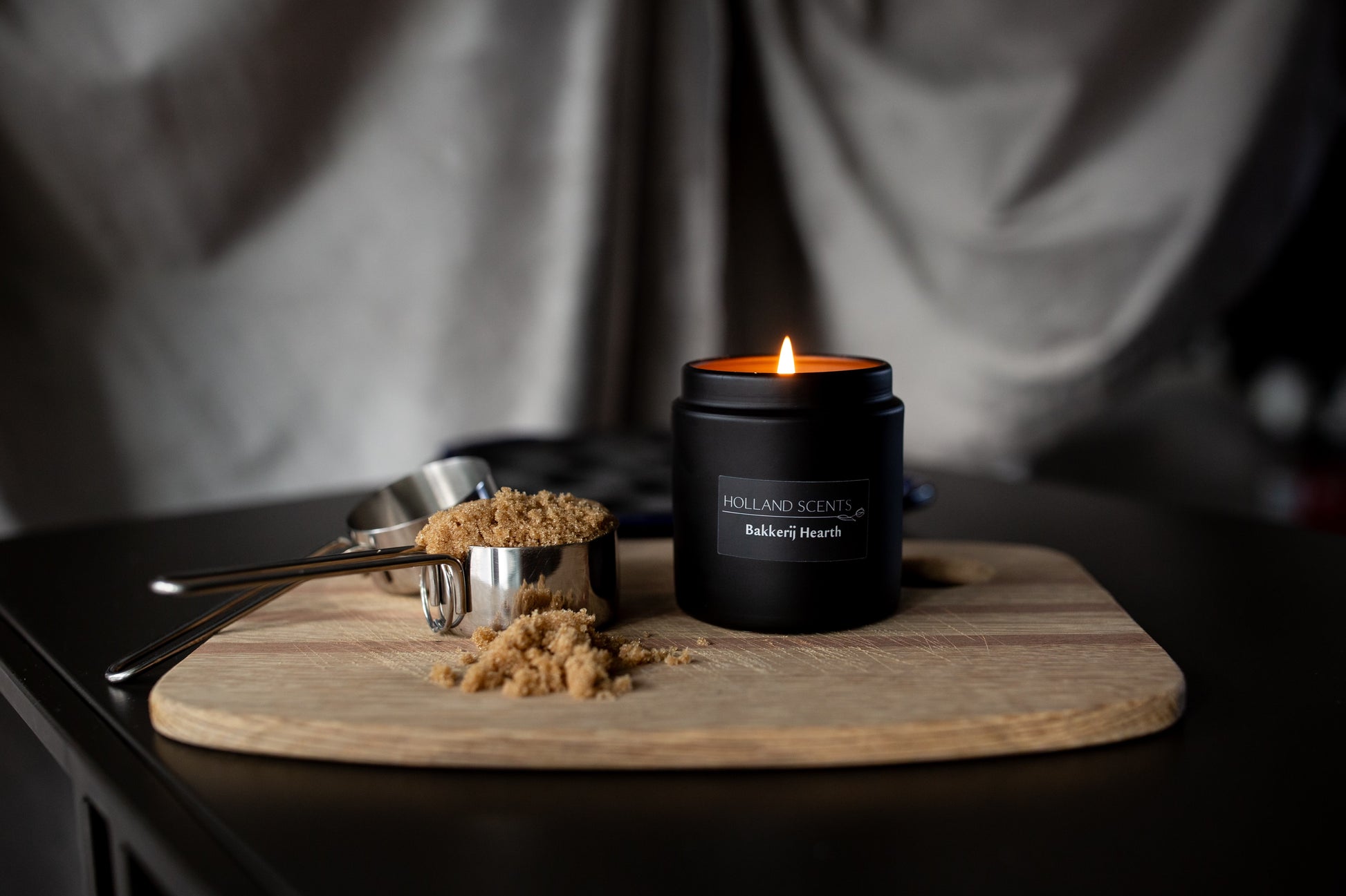 Lit Holland Scents Bakkerij Hearth soy candle beside brown sugar and measuring cups on a wood board, Pella, Iowa
