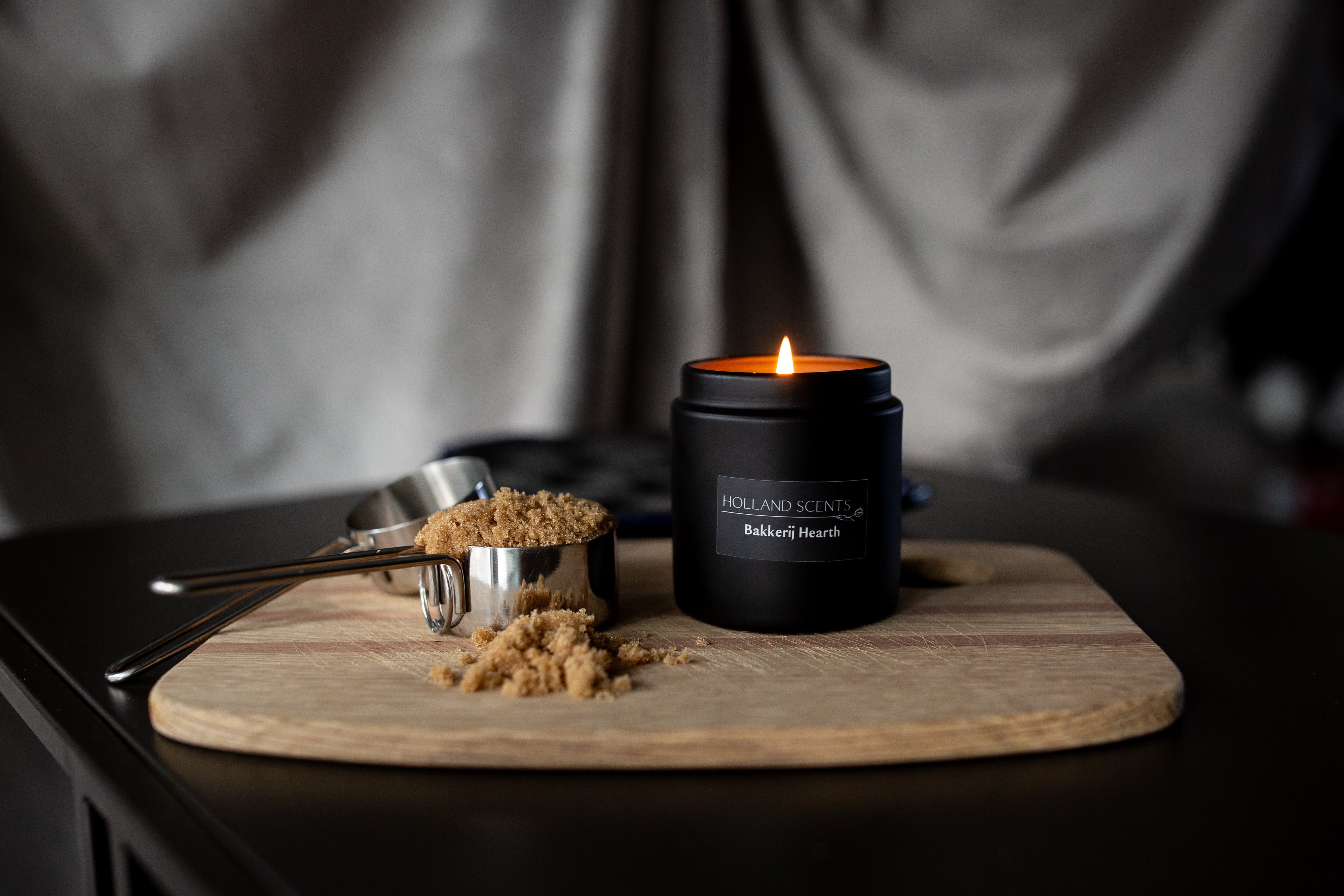 Lit Holland Scents Bakkerij Hearth soy candle beside brown sugar and measuring cups on a wood board, Pella, Iowa
