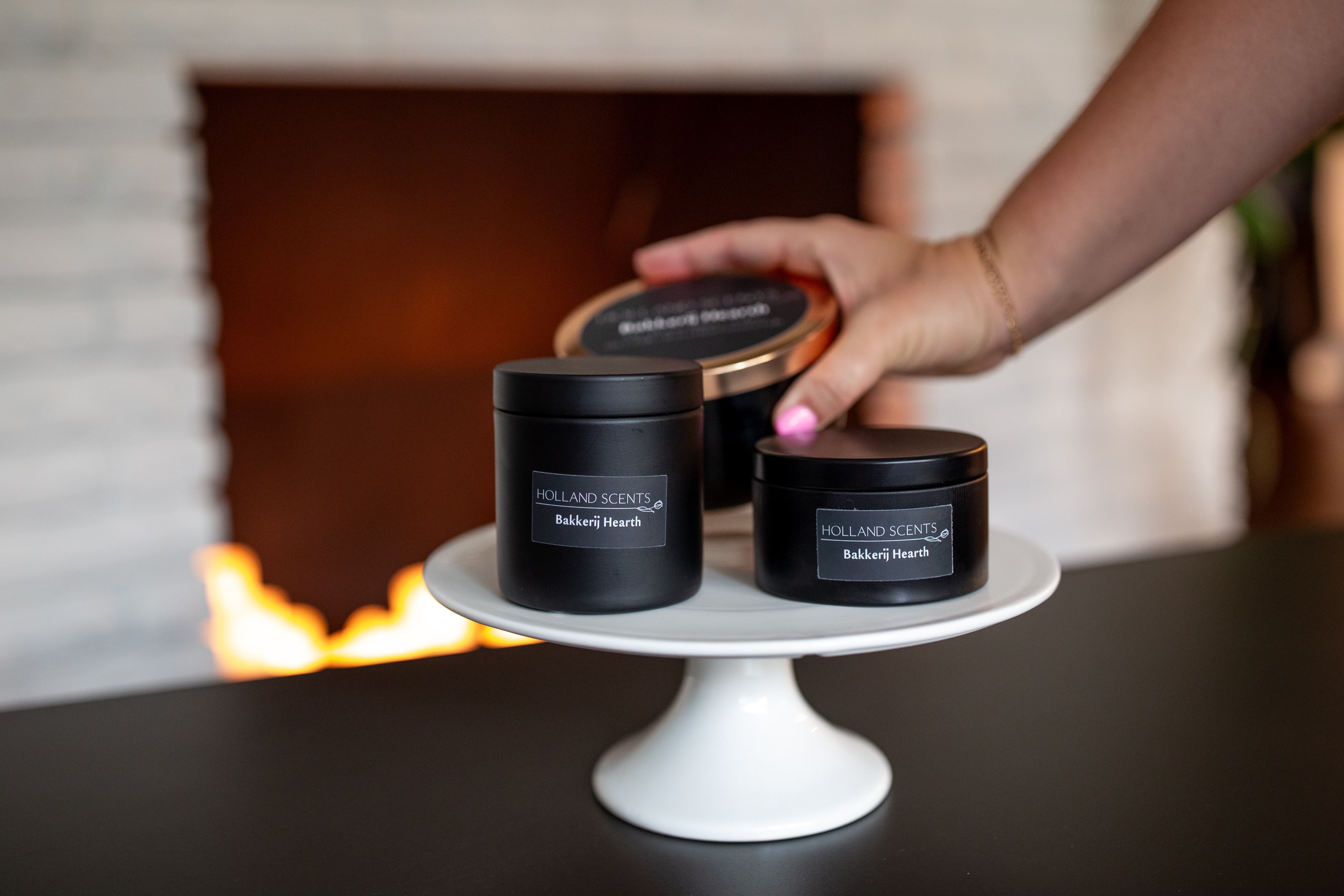 Bakkerij Hearth soy candles on a white cake stand near a lit fireplace, Pella, Iowa