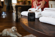 Holland Scents Dutch Clean soy candle on a table with folded towels and a dog in the background, Pella, Iowa