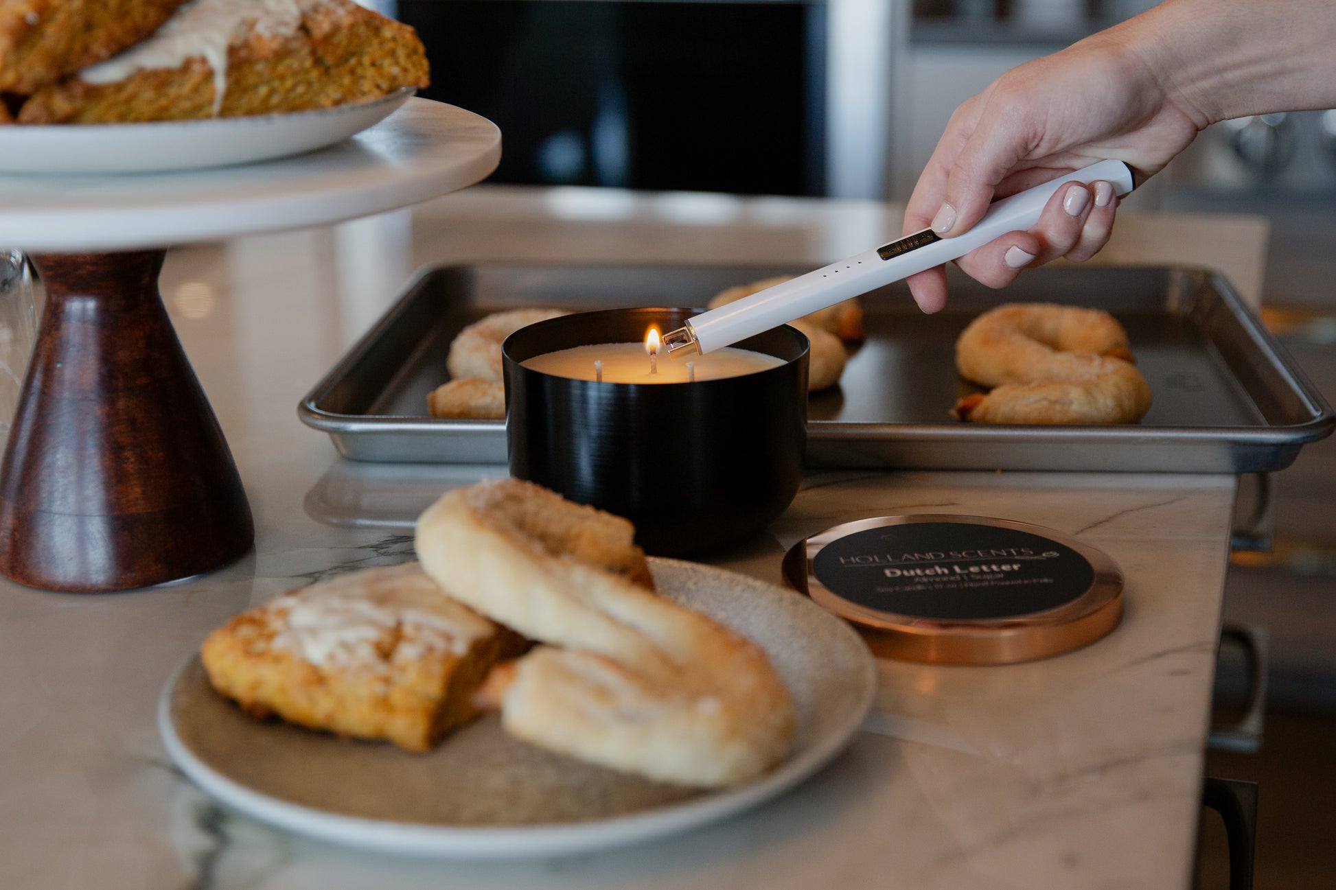 Holland Scents Dutch Letter soy candle being lit beside fresh baked pastries, Pella, Iowa