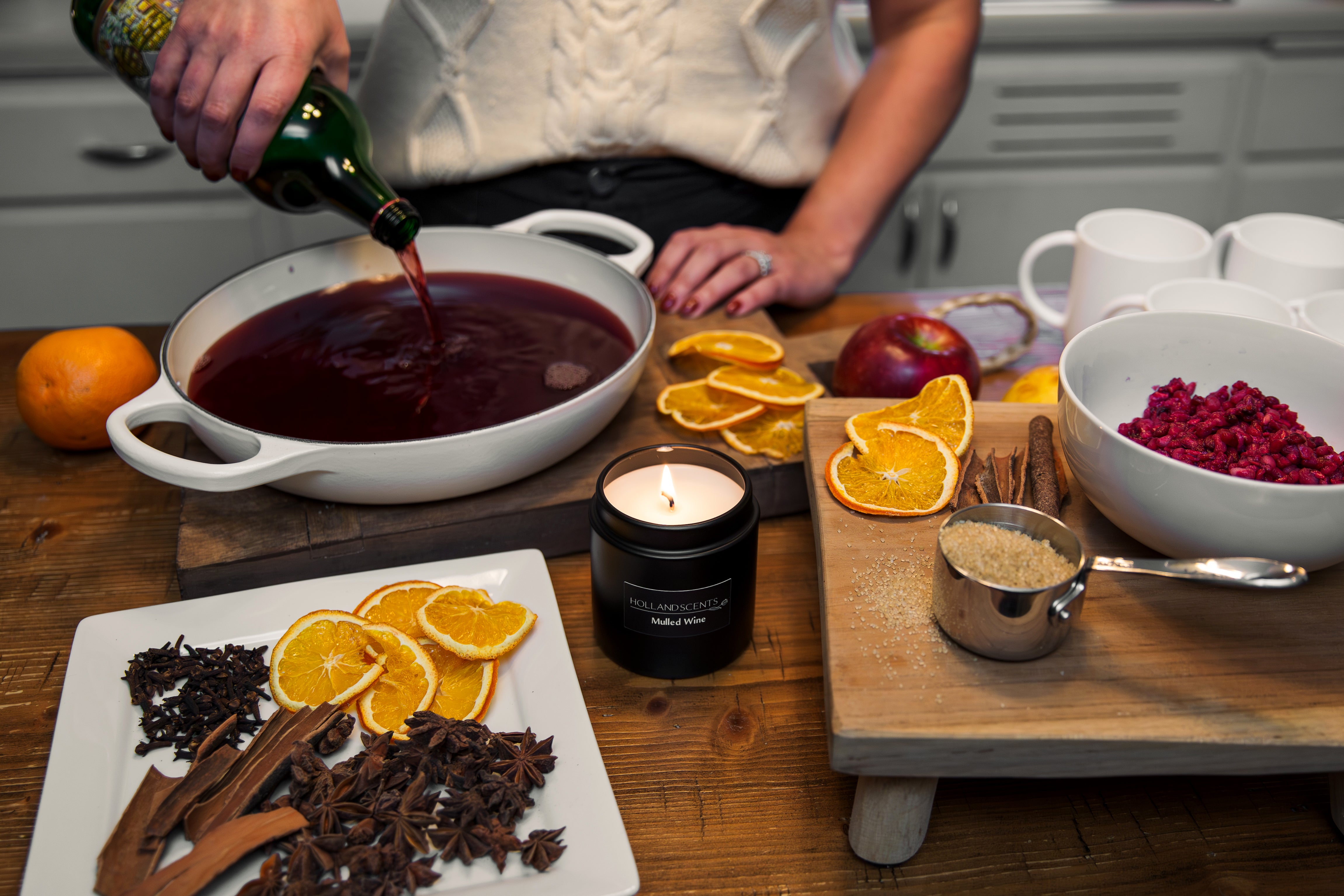 Holland Scents Mulled Wine soy candle on a kitchen table with mulled wine, orange slices, and warm spices, Pella, Iowa