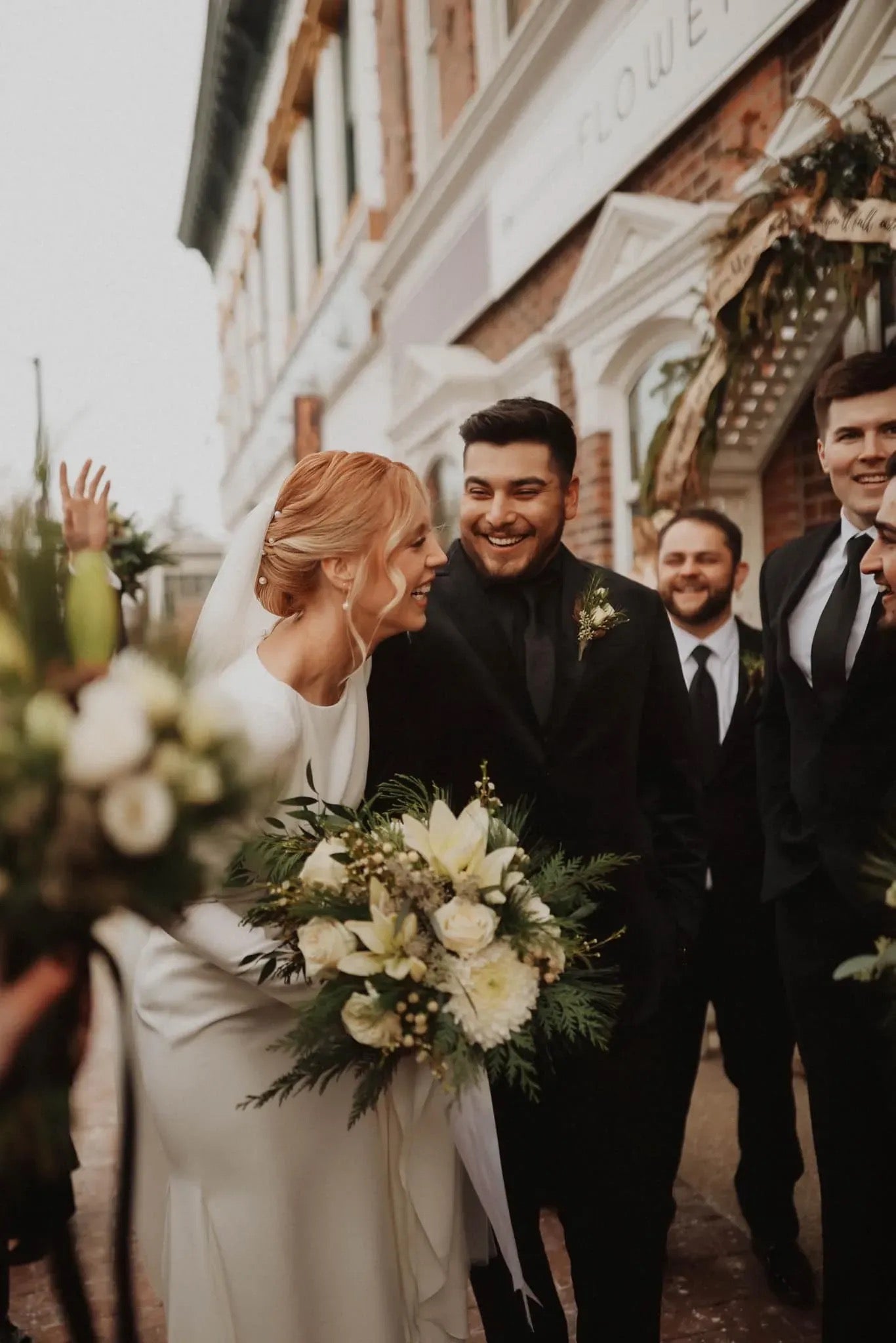 Winter wedding florals with winter greens and white blooms outside Thistles Flower Market, Pella, Iowa