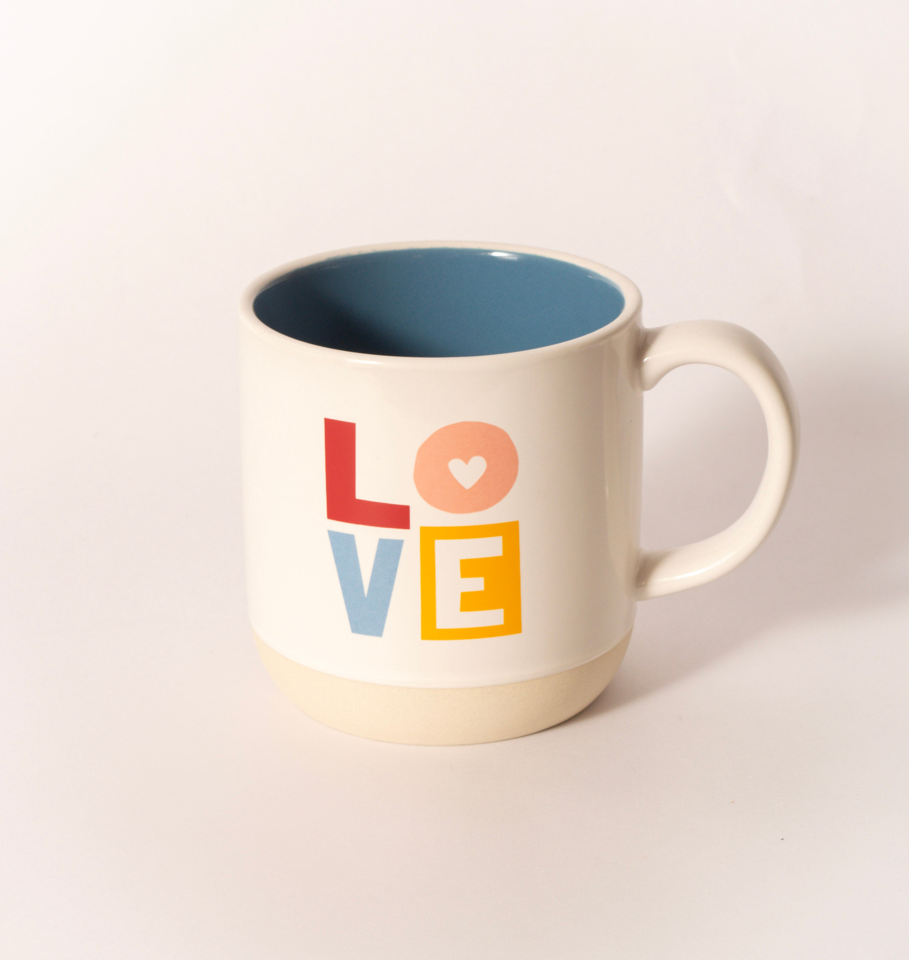 White ceramic mug with colorful "LOVE" lettering, sold at Thistles in Pella, Iowa