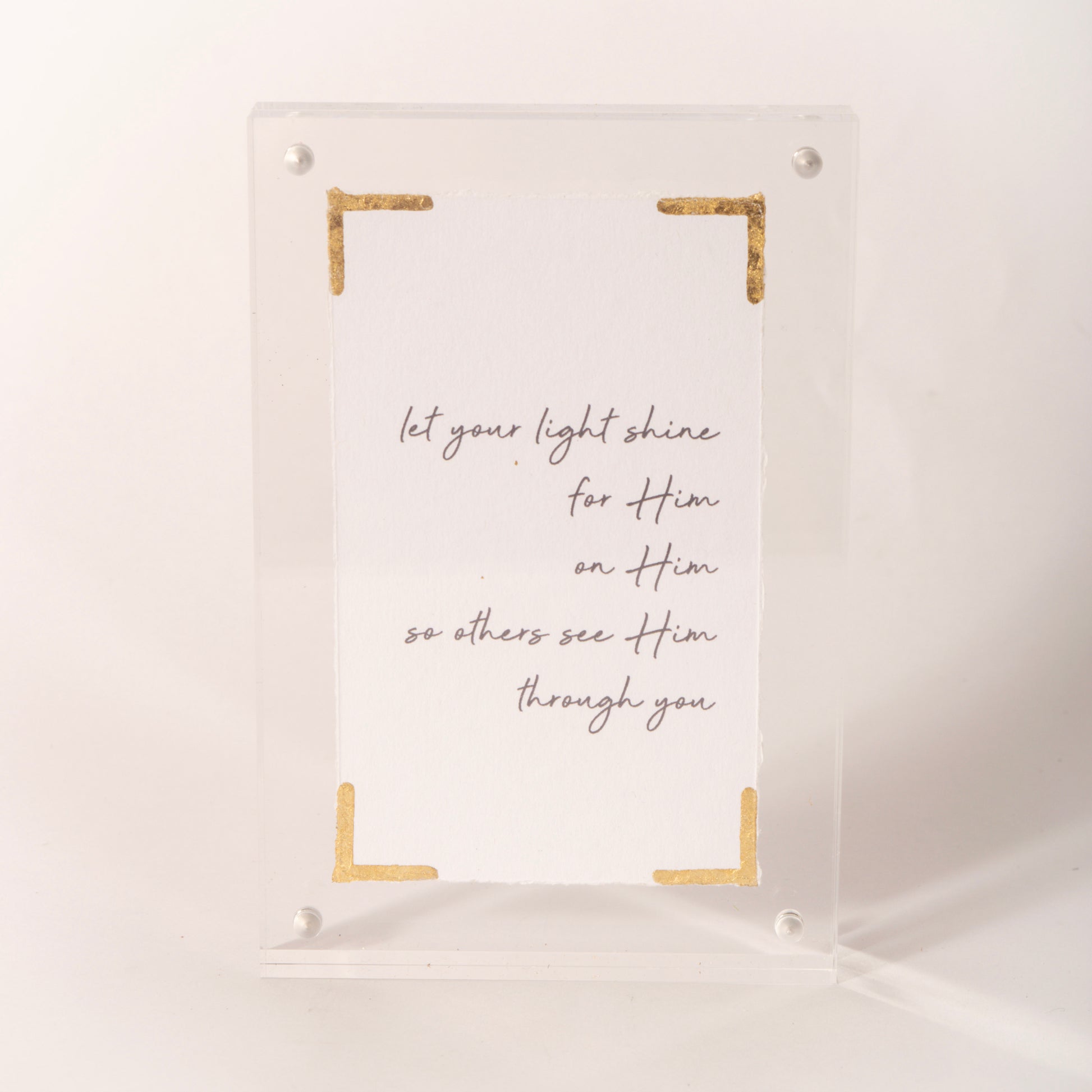 Clear acrylic plaque with gold corner accents reading "let your light shine," sold at Thistles in Pella, Iowa