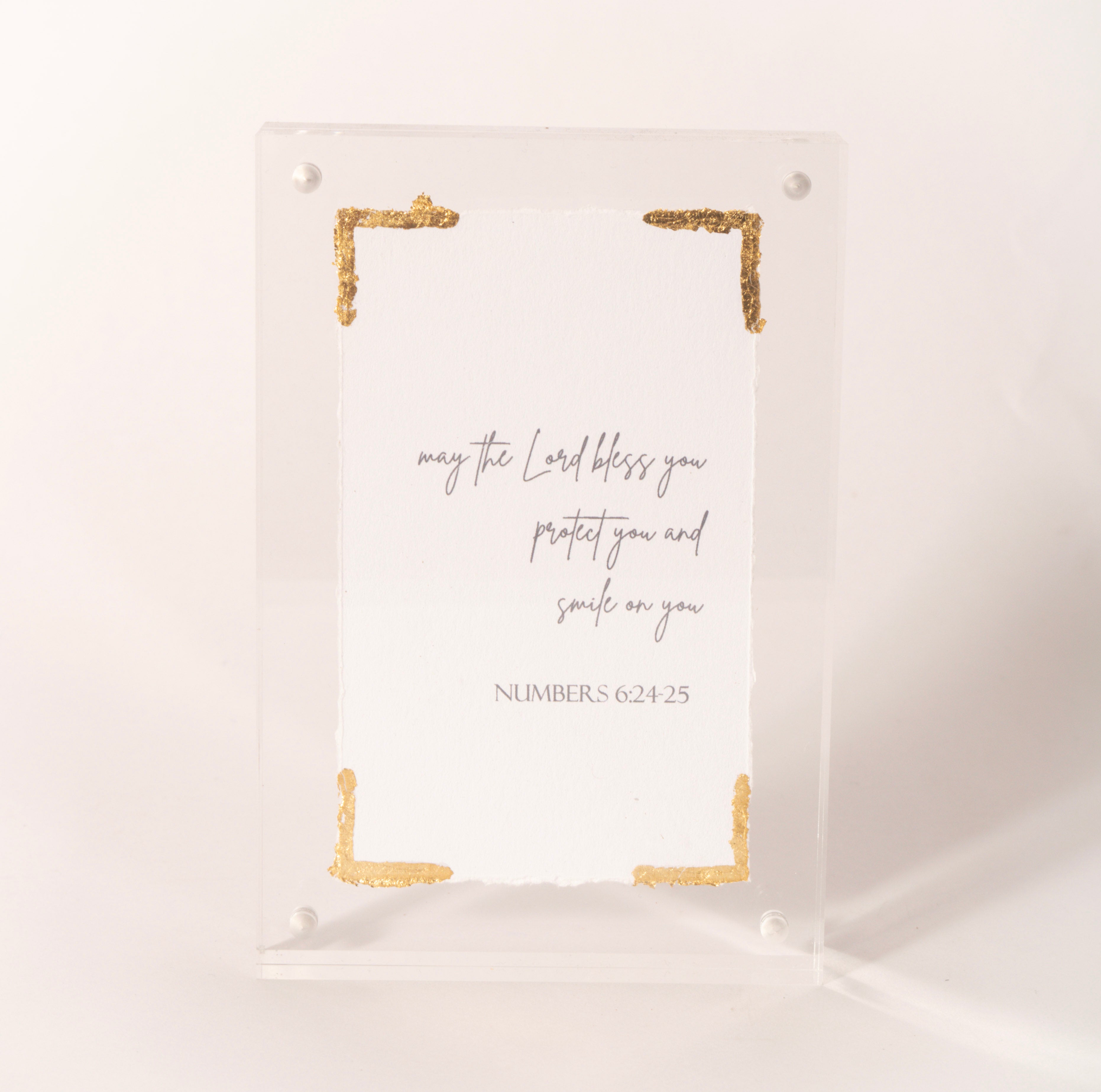 Clear acrylic plaque with gold corners inscribed with the Numbers 6:24-25 blessing, sold at Thistles in Pella, Iowa