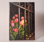 Canvas print of tulips growing through a wrought iron fence, sold at Thistles in Pella, Iowa